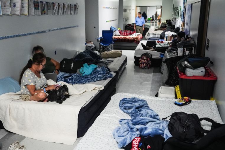 People sleep on mattresses in a school hallway