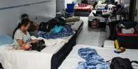 People sleep on mattresses in a school hallway