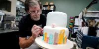 Jack Phillips decorates a white fondant cake in his shop