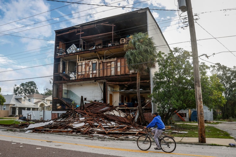 A three story home with the entire front side torn off, with debris scattered in front of it