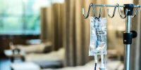 Focus on IV bag and stand in empty hospital ward