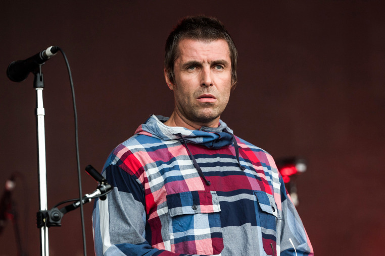 Liam Gallagher on stage next to a mic stand