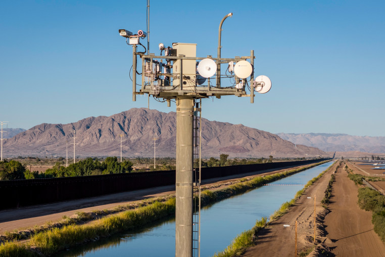 Cameras on a surveillance tower monitor, mountain landscape in the distance