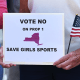 A woman holds a sign to vote no for proposition 1 